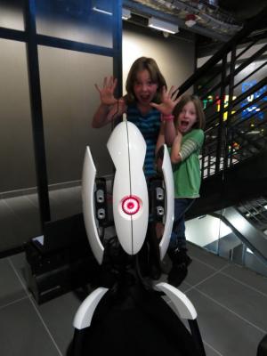 Sylvia and sister Talulah sitting behind a full size Portal Turret at Valve Software headquarters on September 14th, 2012