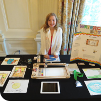 Sylvia standing behind her science fair table at the White House, ready to display the WaterColorBot.