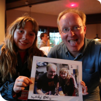 Sylvia posing with Ben Heckendorn, holding a picture of them the previous year