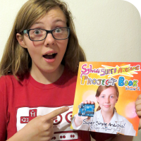 Sylvia pointing at a physical copy of her new book, "Sylvia's Super Awesome Project Book: Super-Simple Arduino"