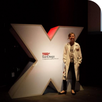 Sylvia posing in front of the prop "X" on stage at TEDx San Diego 2013 before her talk