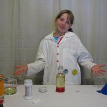 Sylvia stands in front or her lab table with all the ingredients layed out