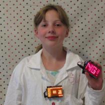 Sylvia holds two Arduinos with LOL Shields displaying messages