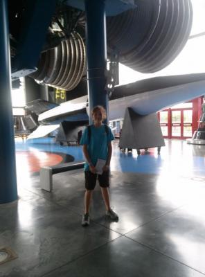 Sylvia standing in front of a set of giant rocket nozzles, and a huge rocket body at NASA Space camp in Alabama.