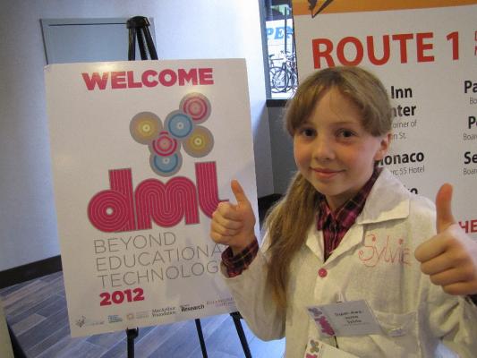 Sylvia gives two thumbs up in front of the DML 2012 Sign in the hotel lobby