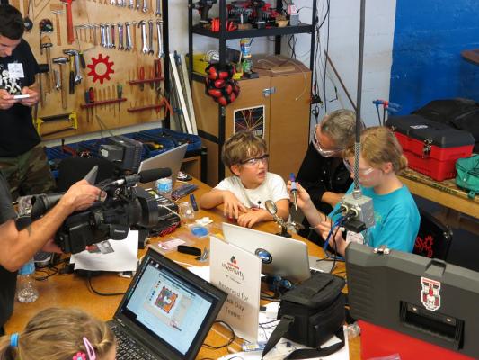 Sylvia helps solder a watch kit with Xeni Jardin and a fan at the Boing Boing Ingenuity hack day