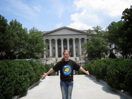 Sylvia poses outside the back of the White House with her arms in the air.