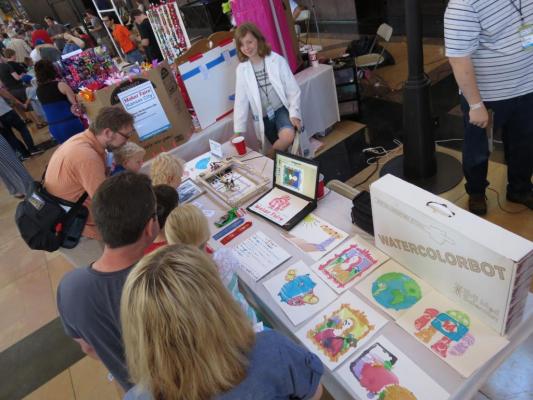 Sylvia standing behind her table at Maker Faire Kansas City