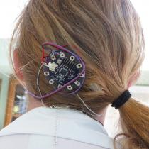 The back of Sylvia's head showing the Lilybad Arduino attached to her hair