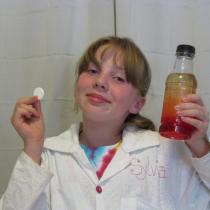 Sylvia holds a fizzy antacid tablet and a bottle of oil and colored water